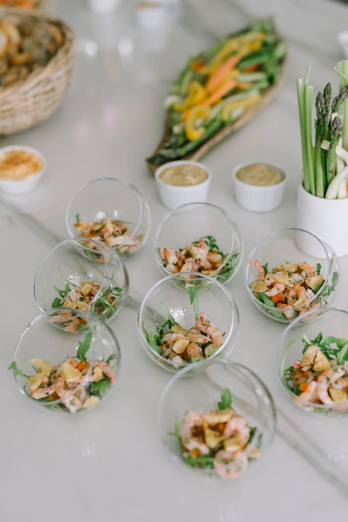 Delicious shrimp appetizers served in glass bowls on a white buffet table, garnished with fresh vegetables.