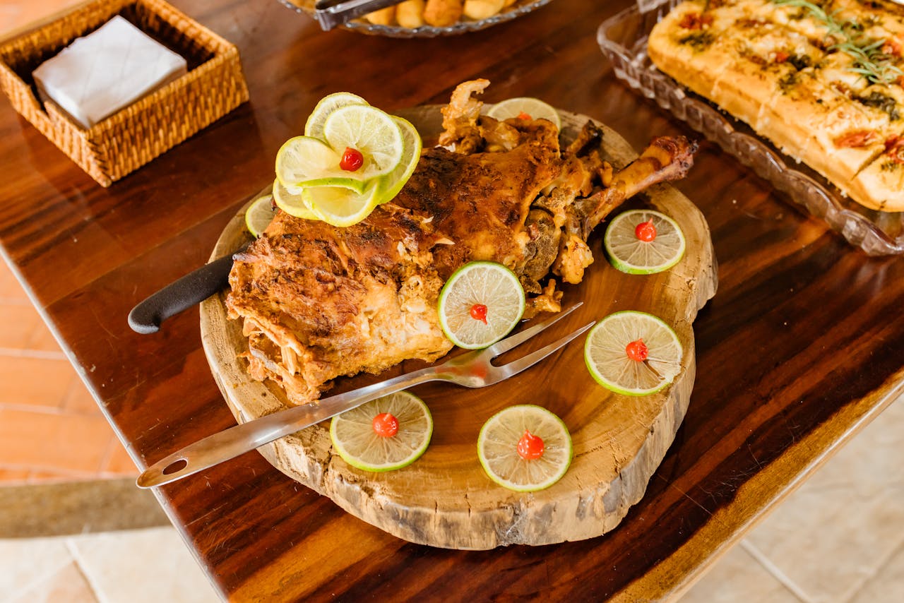 Delicious roasted lamb served with lime slices and garnishes on a wooden platter.