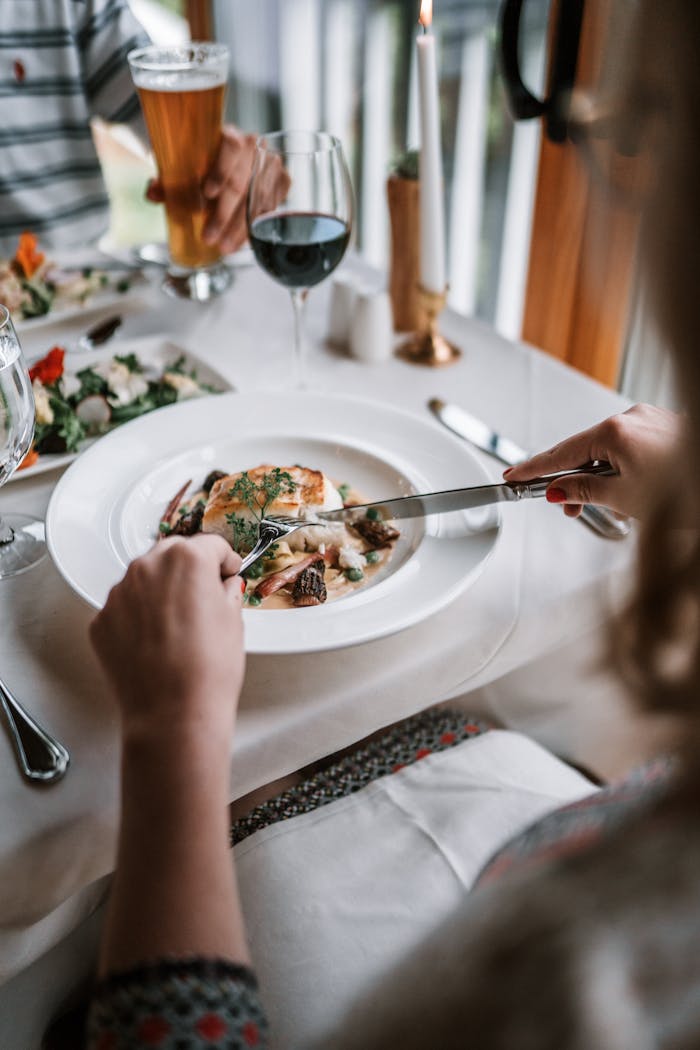 Close-up of a person's hands enjoying a meal at a restaurant table.